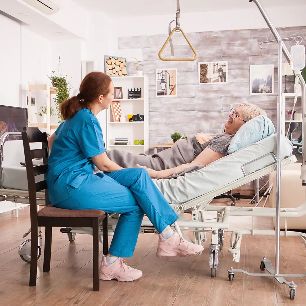 Examinierte Pflegefachkraft betreut ältere Patientin im Pflegebett zu Hause – häusliche Intensivpflege Hamm.